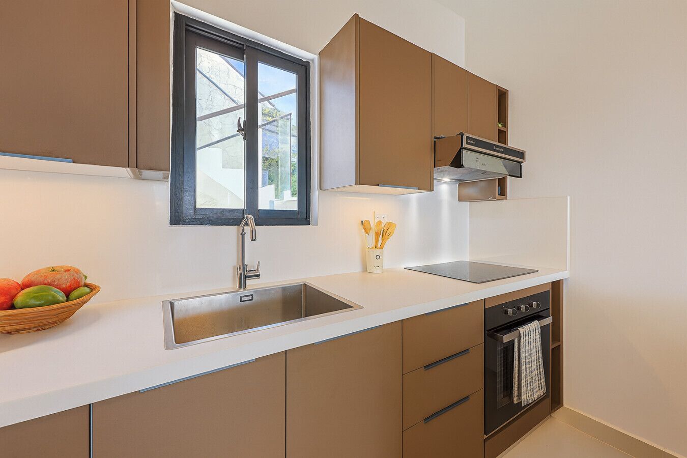 A modern kitchen with a built-in oven, a stainless steel sink, and a window above the sink.
