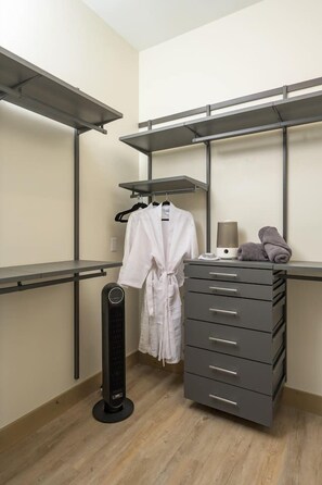 Un dressing accessible sans porte, doté d’une armoire avec des portes miroir, d’un radiateur et d’un porte-serviettes.