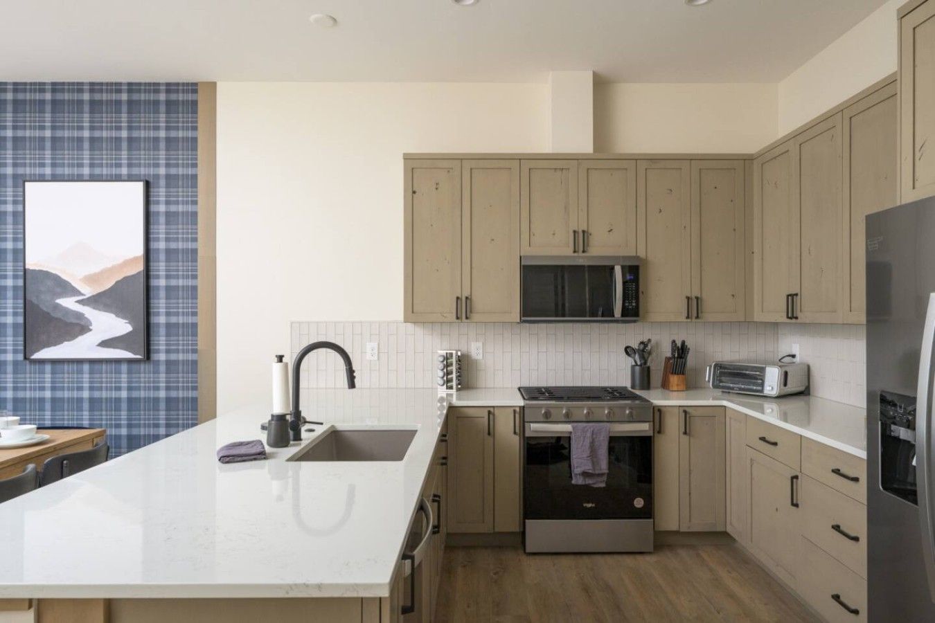 Une cuisine moderne dotée d’un îlot central, d’appareils électroménagers en acier inoxydable et de meubles de couleur claire.
