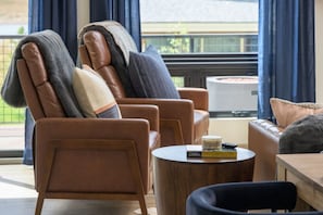 Een moderne woonkamer met leren fauteuils, een ronde houten salontafel en een bank.
