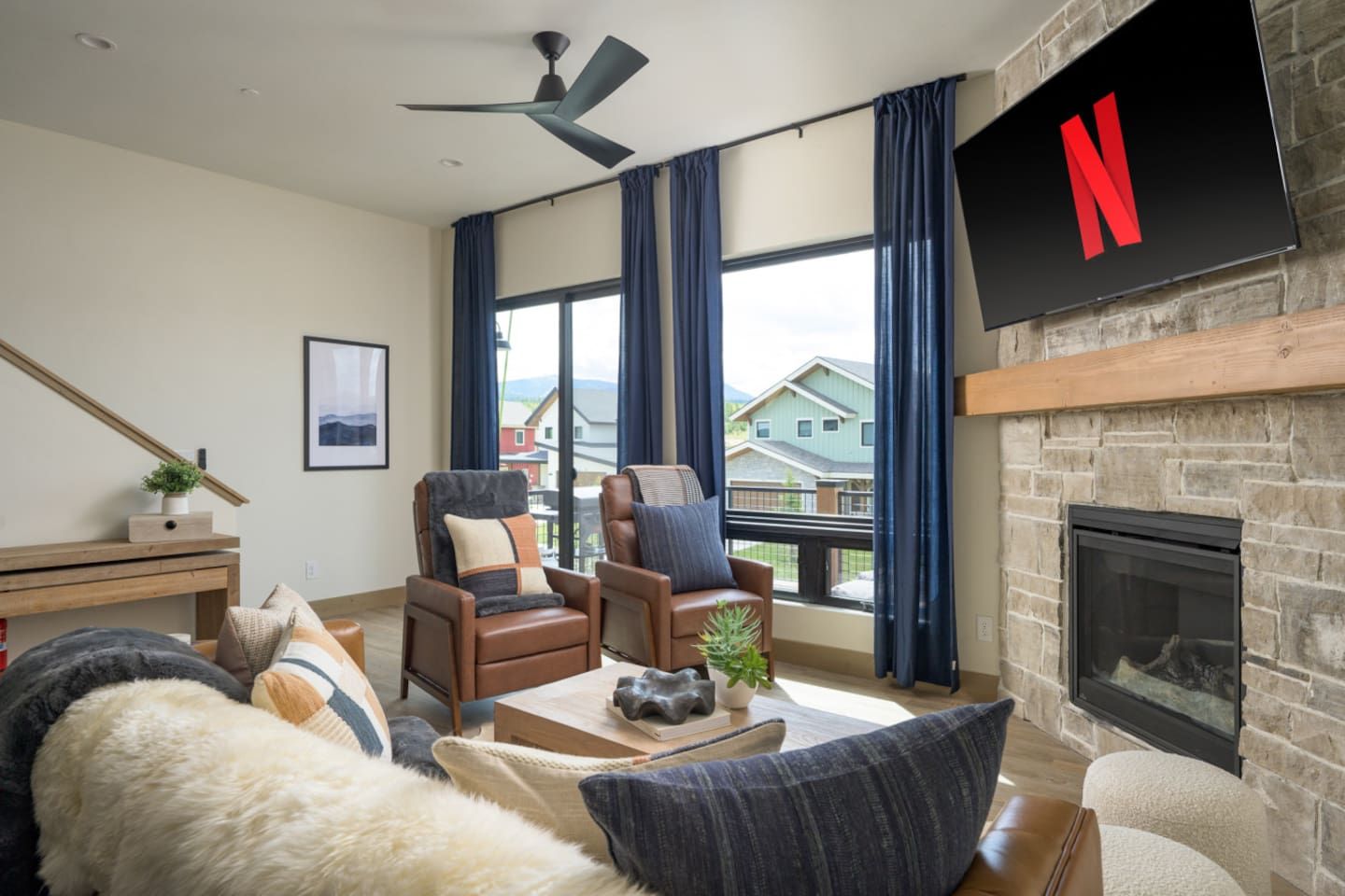 Una sala de estar con chimenea, un televisor de pantalla plana montado en la pared y vistas al exterior.