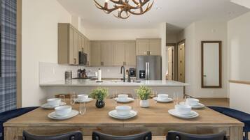 A modern kitchen with a central island, stainless steel appliances, and a dining area with a wooden table set for six.