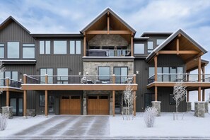 Un immeuble à plusieurs étages, doté d’une façade en pierre, de grandes fenêtres et d’une entrée couverte avec des portes en bois.