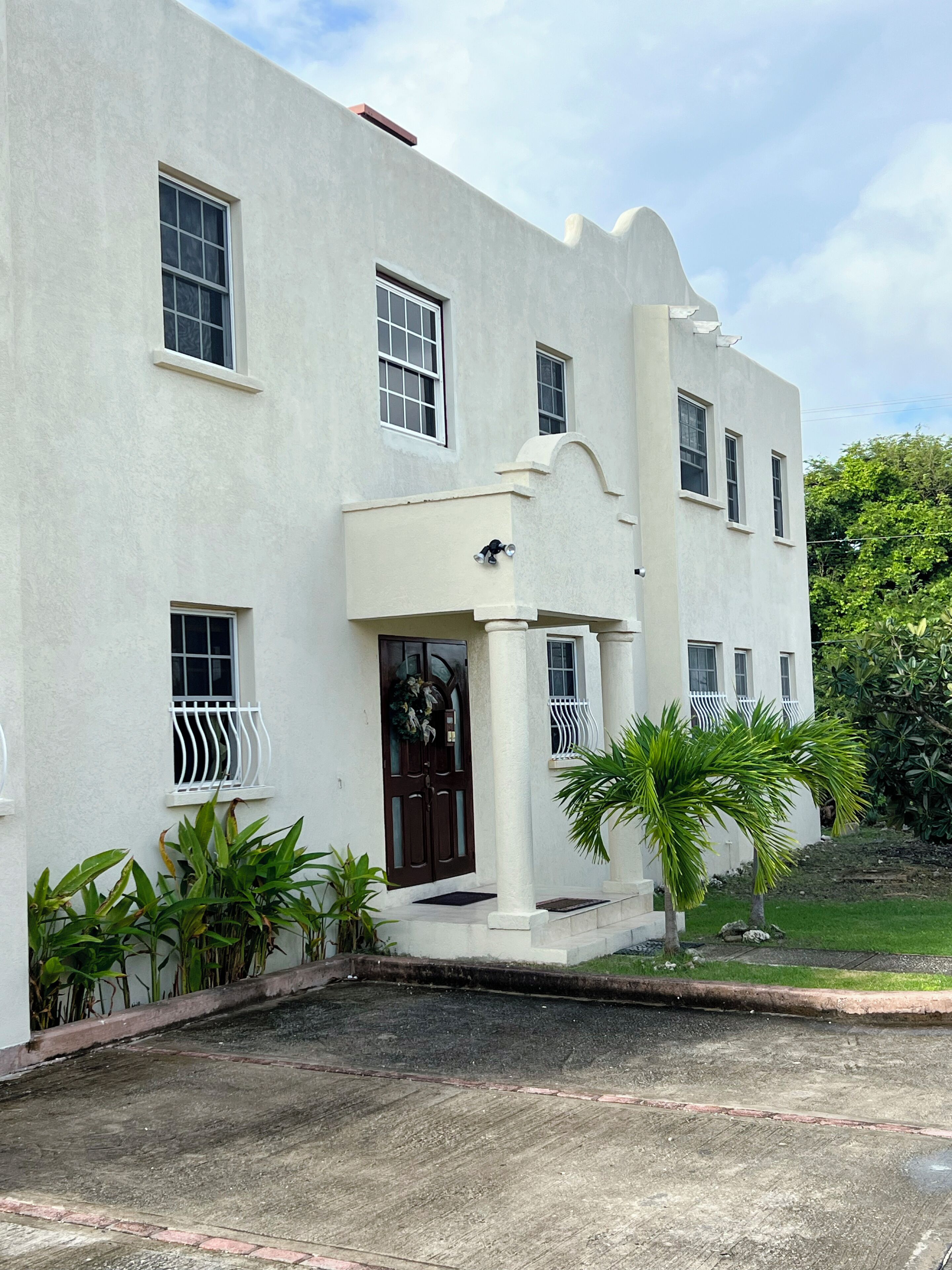 Um edifício branco com várias janelas e uma entrada central com porta.