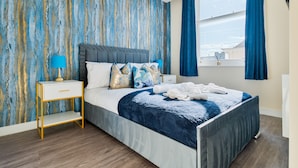 Una camera da letto moderna con un letto grande, un comodino e vista sulla città attraverso una finestra.