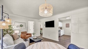 A modern living room with a round coffee table, a brown leather sofa, and a hanging wicker chandelier.