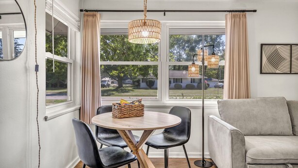 A dining area with a round table, black chairs, and a wicker basket.