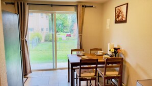 A dining area with a table set for four, a sliding glass door leading to a garden, and a framed picture on the wall. - Getaway Spot Close to Red Rocks, Denver, Mtns (Lakewood)