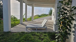 A covered outdoor area with a bench, concrete pillars, and a view of the landscape.