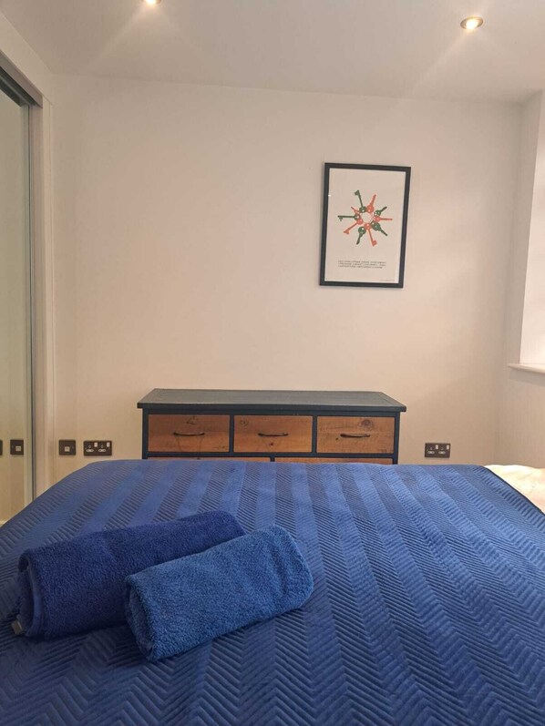 Une chambre à coucher avec un lit, une commode et un tableau encadré au mur.