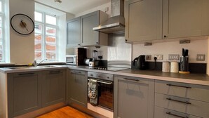 Una cocina moderna con armarios grises, horno empotrado y ventana que proporciona luz natural.