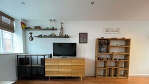 Una sala de estar con un mueble bajo de televisión de madera, una estantería de madera y un comedor con una mesa y sillas.