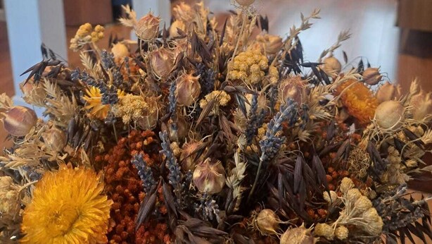 Una sala de estar con un sofá, una mesita de centro y un arreglo decorativo de flores secas al frente.
