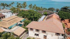 A coastal residential area with houses, a swimming pool, and palm trees.