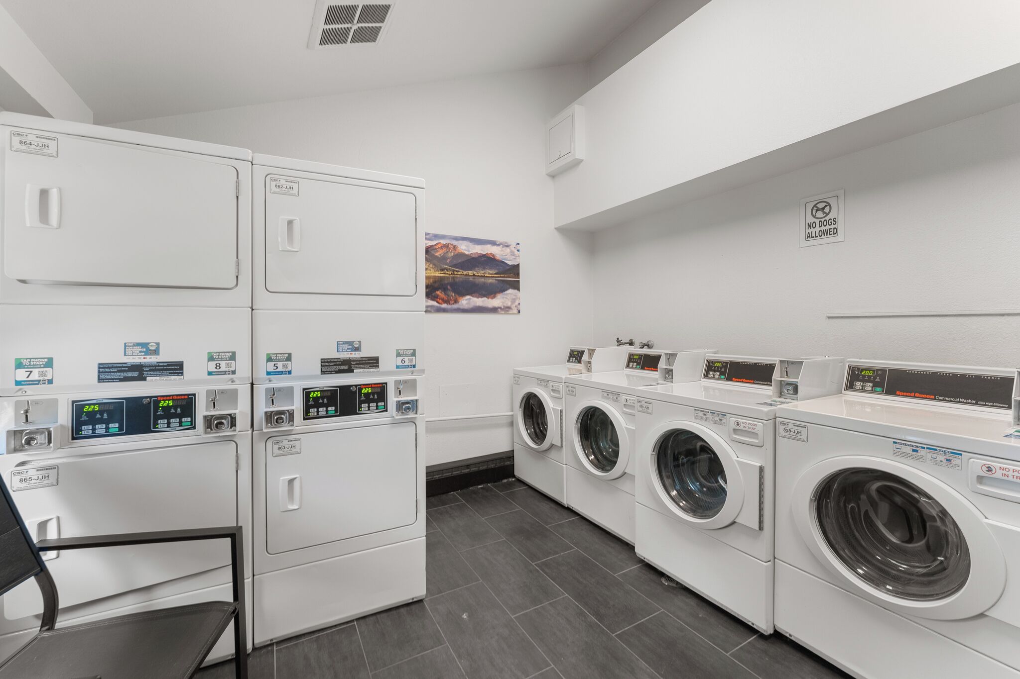 A laundry facility with stacked dryers and front-loading washers.