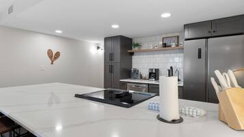 Uma cozinha moderna com uma ilha grande, eletrodomésticos de aço inoxidável e bancada de mármore branco.