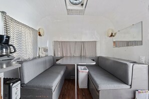 Un intérieur de camping-car compact comprenant un coin cuisine, des siÚges gris et une petite table.