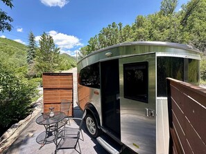 A recreational vehicle with a covered patio area, a table, and chairs.