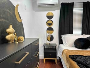 A bedroom with a bed, a dresser, a nightstand, and a wall with circular decorations.