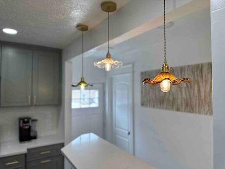A kitchen with white countertops, grey cabinets, and pendant lights.. Rise & Shine-Mid Mod House-FirePit-HotTub-Sleeps10