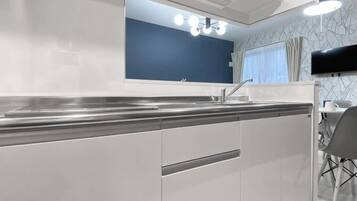 A modern kitchen with a large island, a built-in sink, and a dining area with a chair.