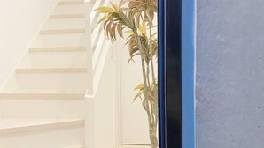 A staircase with white steps leading upwards, a blue-framed window, and a potted plant to the right. - Nestay apartment Tokyo Ginza (Tokyo)