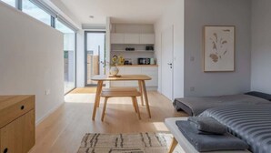 Un dormitorio moderno con una cama grande, un escritorio pequeño y vistas a la ciudad.