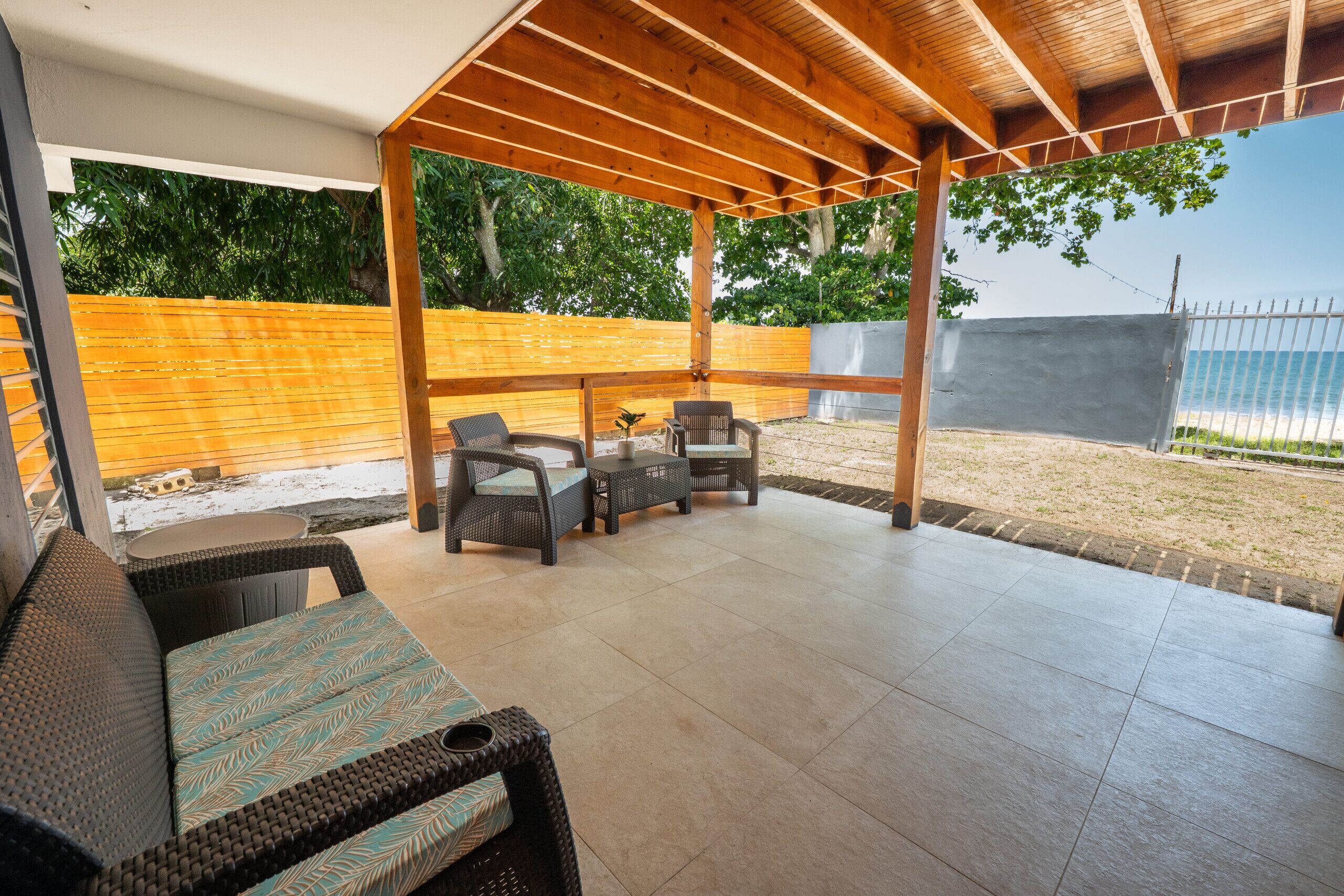 Un'area patio esterna con mobili in vimini e una struttura a pergola.