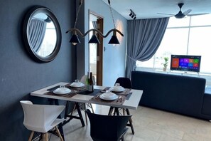 A dining area with a table set for two, a television in the background, and a view of the city through large windows. - Stella @ Vortex Suites KLCC (Kuala Lumpur)