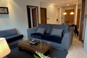 A modern living room with a sofa, a coffee table, and a lamp. - Stella @ Vortex Suites KLCC (Kuala Lumpur)