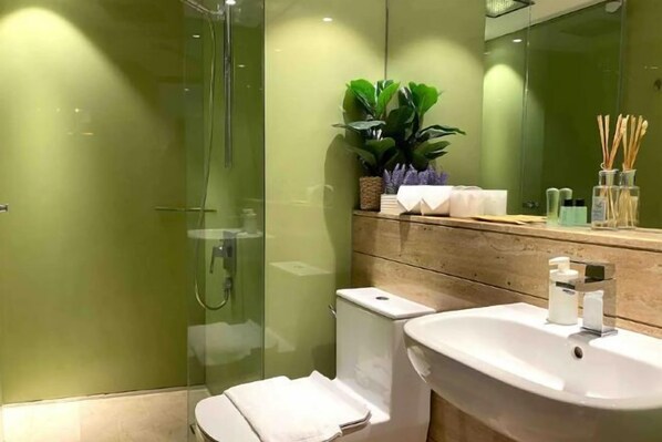 Un baño moderno con cabina de ducha de vidrio, un lavamanos blanco y un mueble de tocador de madera.