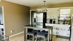 A compact kitchen with a central island, bar stools, and a dining table.