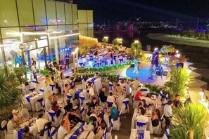 An outdoor event with guests seated at tables, a stage with performers, and a view of the cityscape. - Hera House Vinhomes Grand Park Ho Chi Minh City (Ho Chi Minh City)