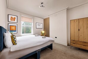 Een slaapkamer met een bed, een kledingkast, een raam en kunstwerken aan de muur.