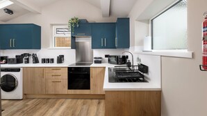 A modern kitchen with wooden cabinets, a stainless steel range hood, a dishwasher, and a window with frosted glass. - 6 Bedroom Victorian Terrace, 3.5 baths (Hensingham)