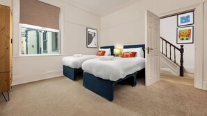 A bedroom with two beds, a window, a door, and a staircase. - 6 Bedroom Victorian Terrace, 3.5 baths (Hensingham)