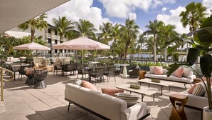 An outdoor patio area with seating arrangements, including sofas and chairs, and umbrellas providing shade.
