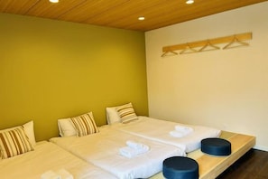 Una habitación con dos camas, cada una con toallas dobladas y un banco de madera.