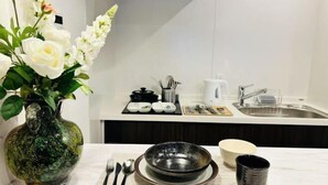 Eine moderne Küche mit Marmorarbeitsplatte, einer Vase mit weißen Blumen und einer Esszeile mit Tellern, Schüsseln und Besteck.