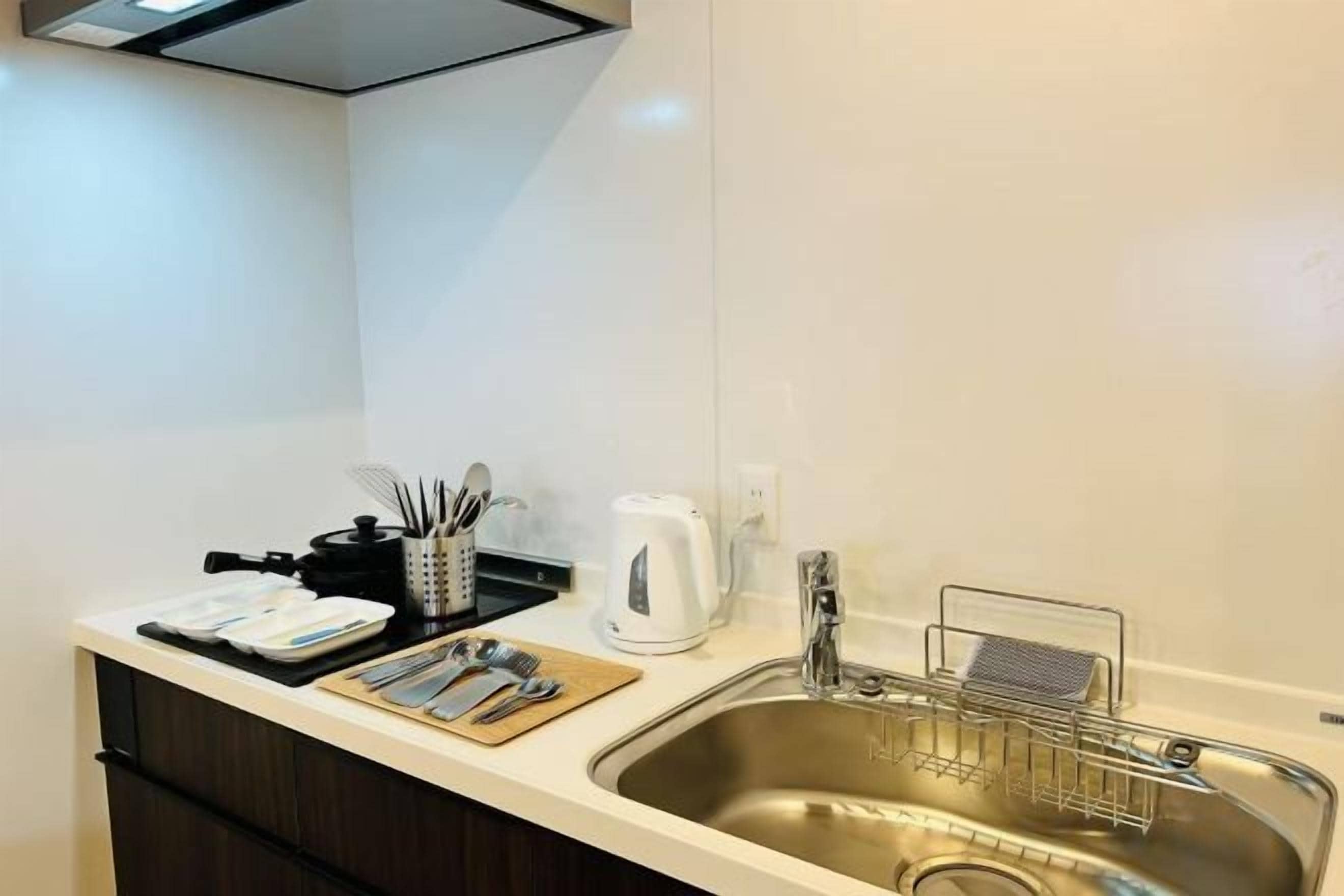 A modern kitchen with a stainless steel sink, a kettle, and a coffee maker on the counter.