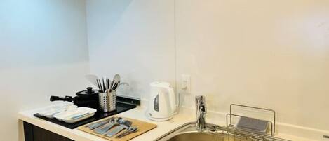 A modern kitchen with a stainless steel sink, a kettle, and a coffee maker on the counter.