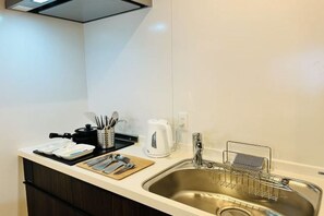 A modern kitchen with a stainless steel sink, a kettle, and a coffee maker on the counter. - ASOBO OSAKA Kuromon 1st (Osaka)