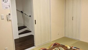Ein Zimmer mit Holzboden, einem Esstisch mit Tassen und einer Vase, sowie einer Treppe zu einem Schrank.