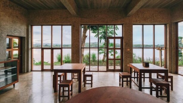 A spacious room with large windows, wooden furniture, and a view of a lake. - Loogmai Guesthouse (Chiang Khan)