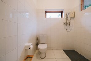 A small, tiled bathroom with a toilet, a shower, and a window. - Loogmai Guesthouse (Chiang Khan)