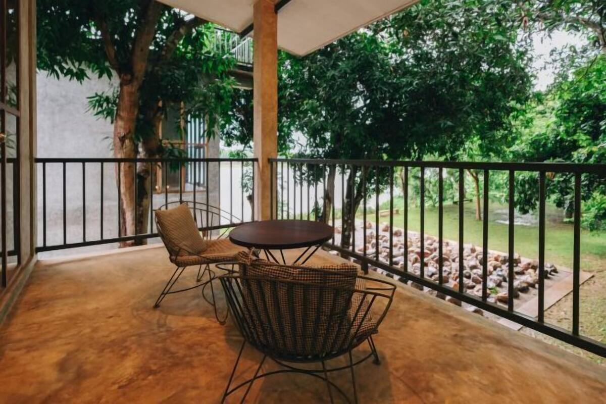 Ein Balkon mit rundem Tisch und zwei Stühlen, umgeben von einem schwarzen Metallgeländer.