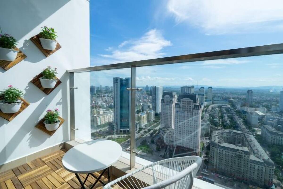 A balcony with a city view, white furniture, and potted plants.