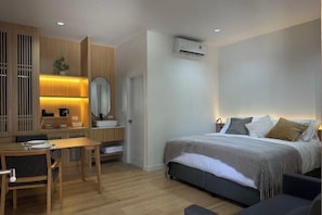 Une chambre d’hôtel moderne équipée d’un lit, d’une table de chevet et d’un petit bureau avec une chaise.