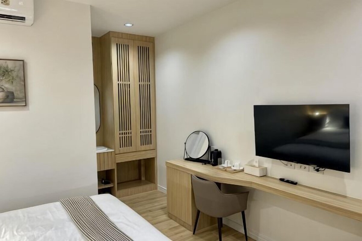 Hotellihuone, jossa on sänky, työpöytä, jossa on televisio, peili ja vaatekaappi.