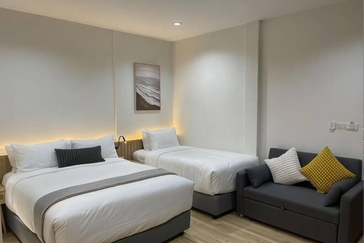 Une chambre d’hôtel avec deux lits, un canapé et une œuvre d’art accrochée au mur.